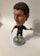 A bobblehead figure of a soccer player wearing a dark jersey with a logo and 'Qatar Airways' printed on it. The figure has short dark hair, light-colored shoes, and is mounted on a round base with the word 'soccerstarz'. The background is neutral, likely a plain surface.