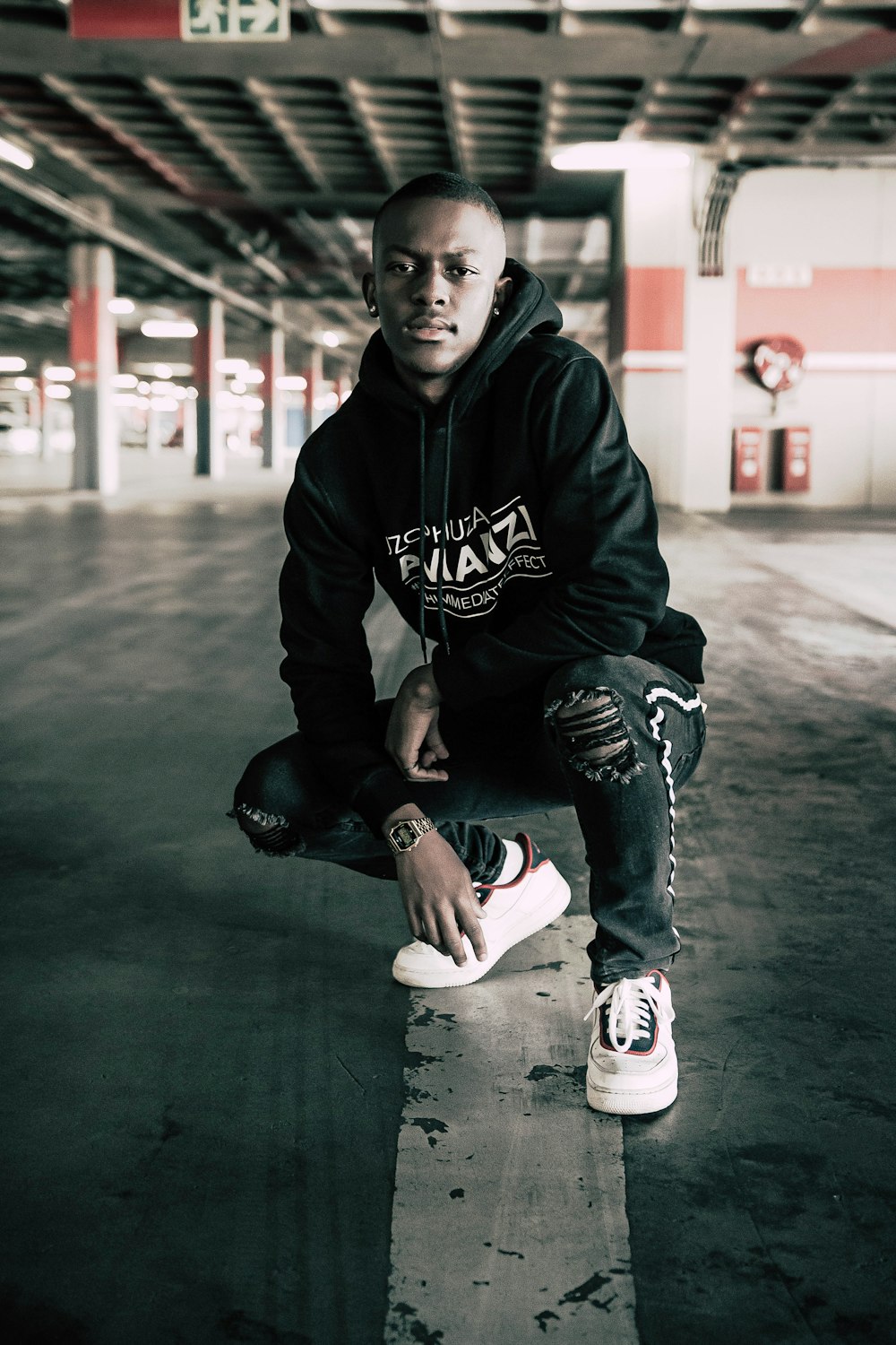 boy in black and white hoodie and blue denim jeans sitting on floor