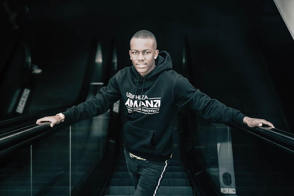 man in black hoodie standing on black tunnel