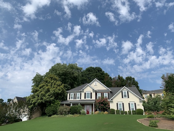 Modern two-story family home with a manicured lawn and clear blue sky background.