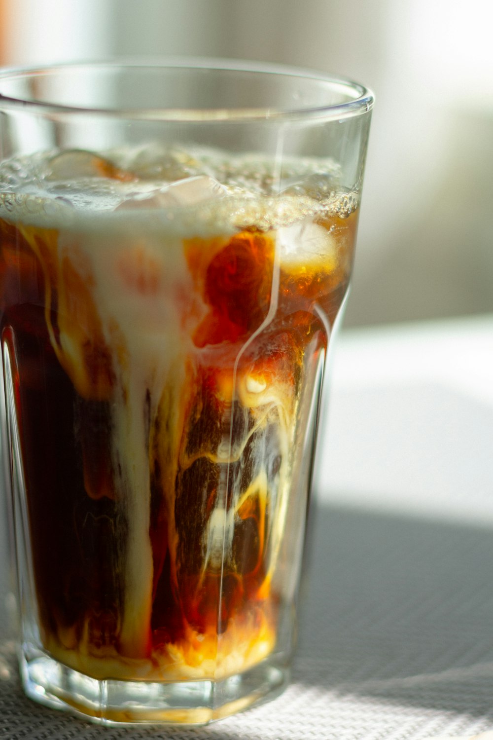 clear drinking glass with ice and brown liquid