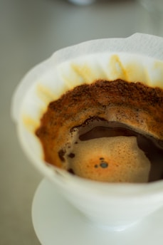 A close-up of a V60 coffee brewer with freshly brewed coffee dripping through the cone.