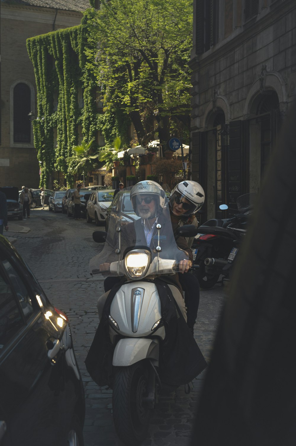 white and black motor scooter parked on sidewalk during daytime