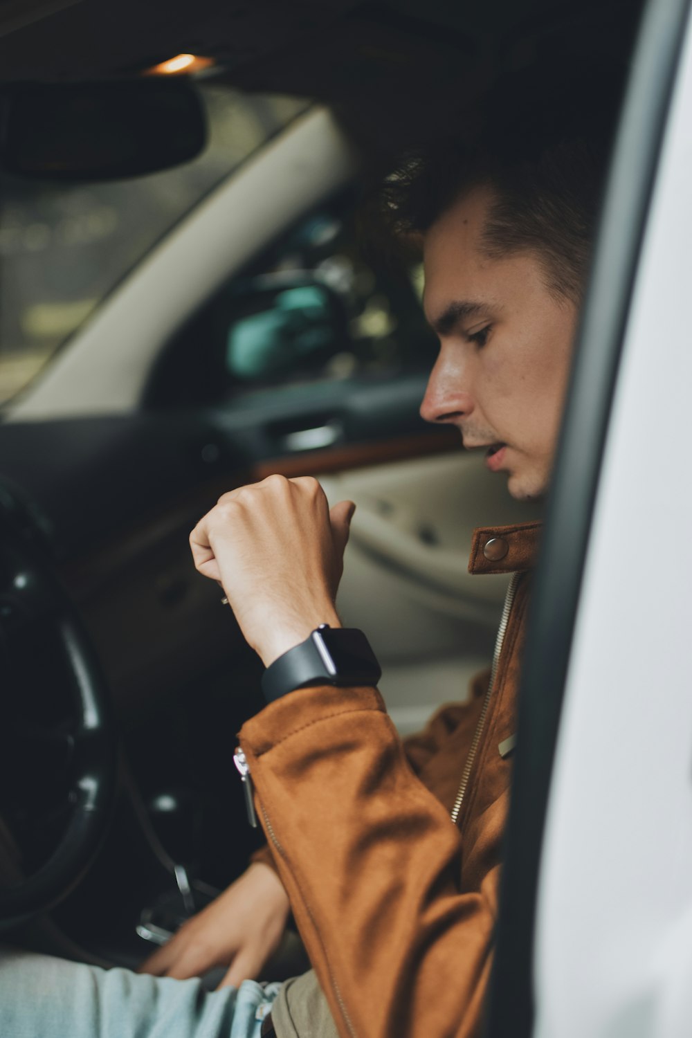man in brown jacket holding car door