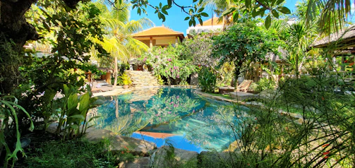 A serene pool villa surrounded by lush tropical greenery at sunset.