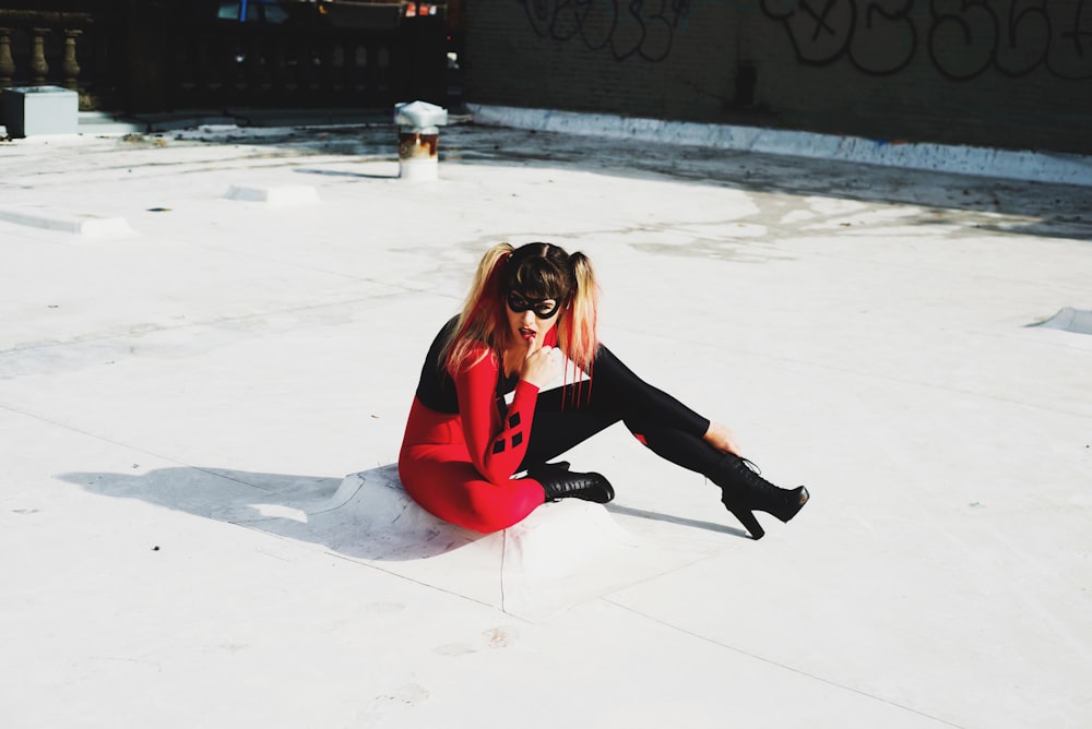 woman in red long sleeve shirt and black pants sitting on snow covered ground during daytime