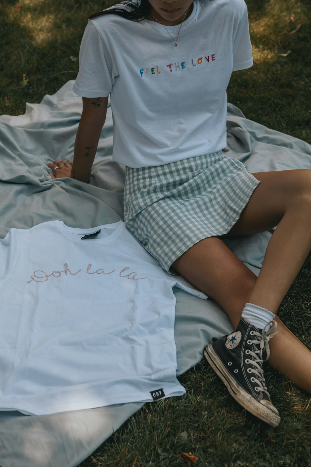 woman in white t-shirt and black and white plaid skirt sitting on white textile