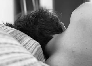 grayscale photo of woman lying on bed