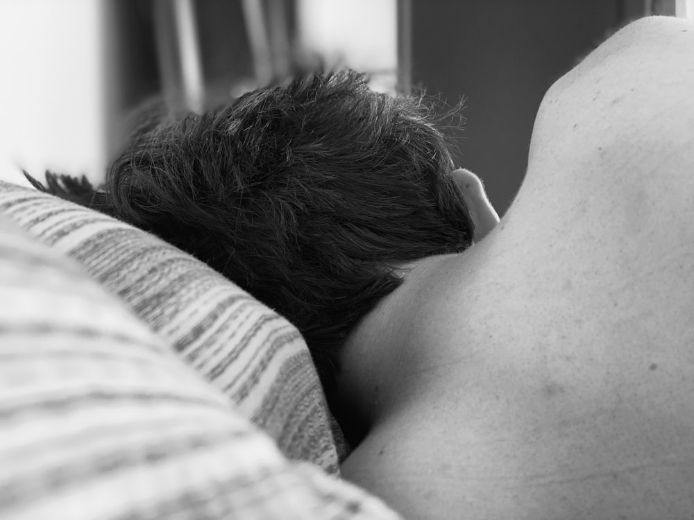 grayscale photo of woman lying on bed