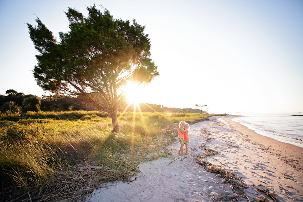 woman in pink tank top and white shorts walking on gray sand near green grass field