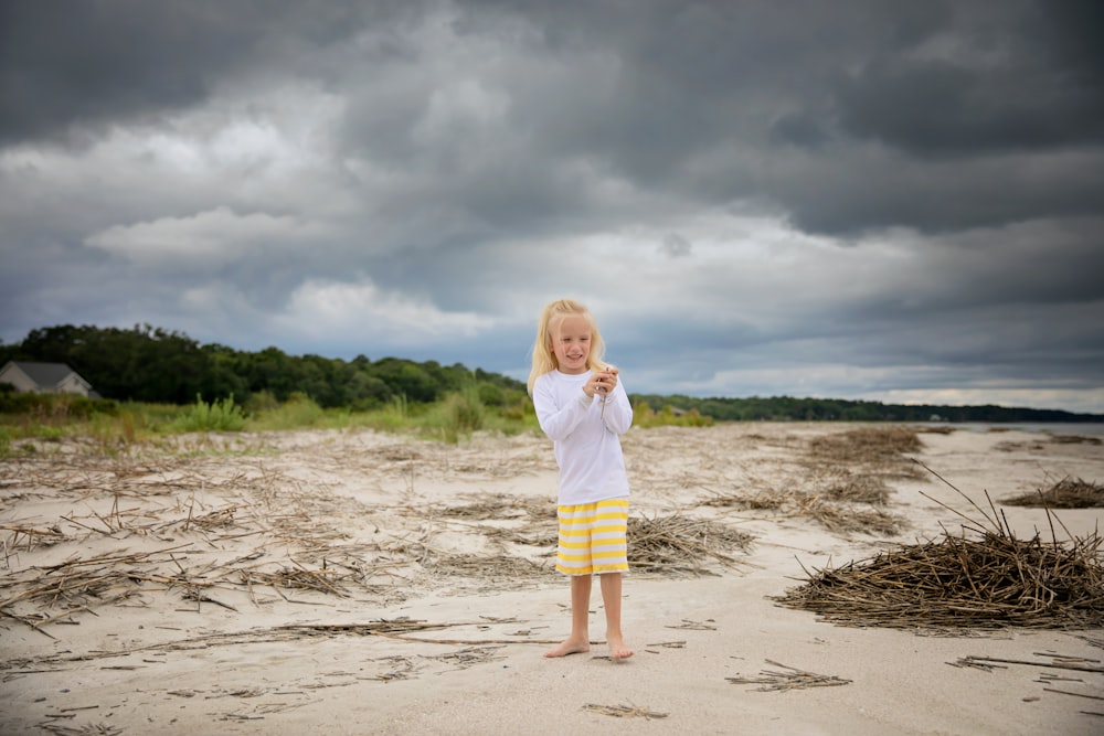 girl in white long sleeve shirt and yellow skirt standing on beach during daytime