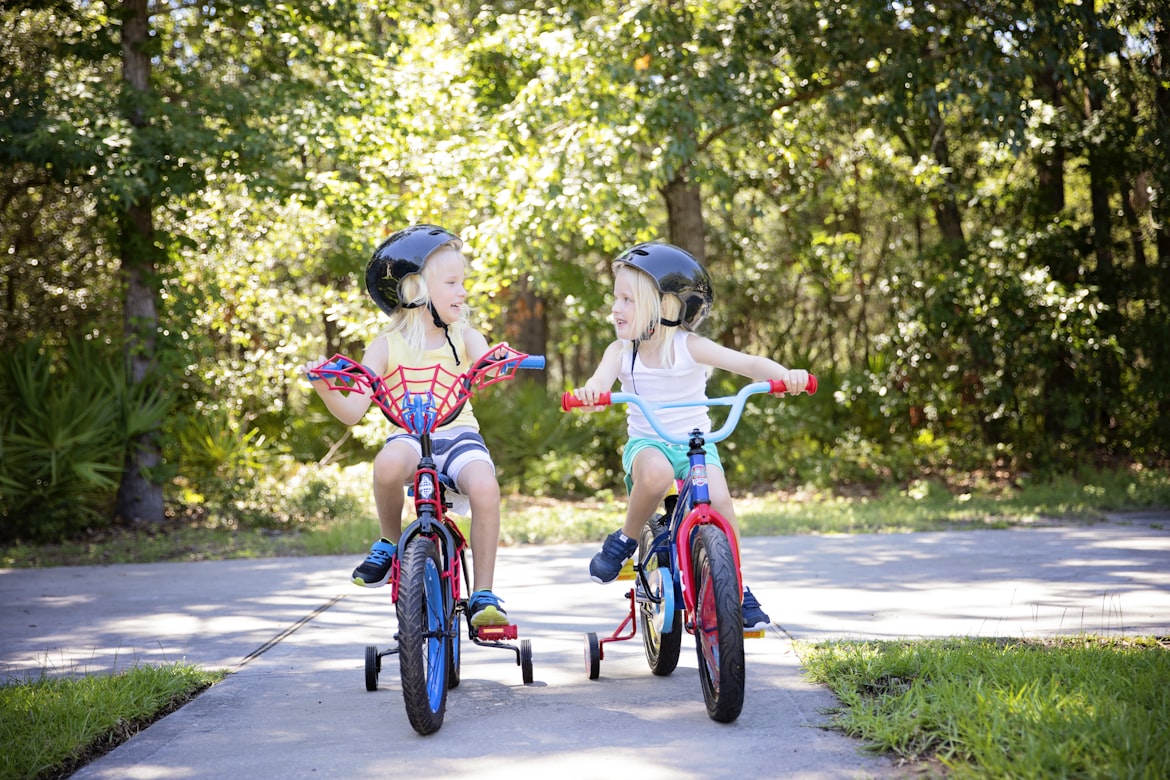 Two children riding bikes with training wheels