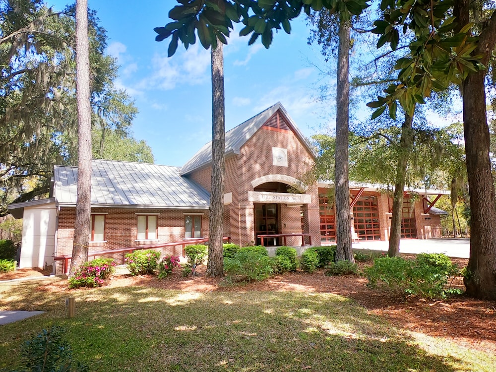 a brick house surrounded by trees and bushes