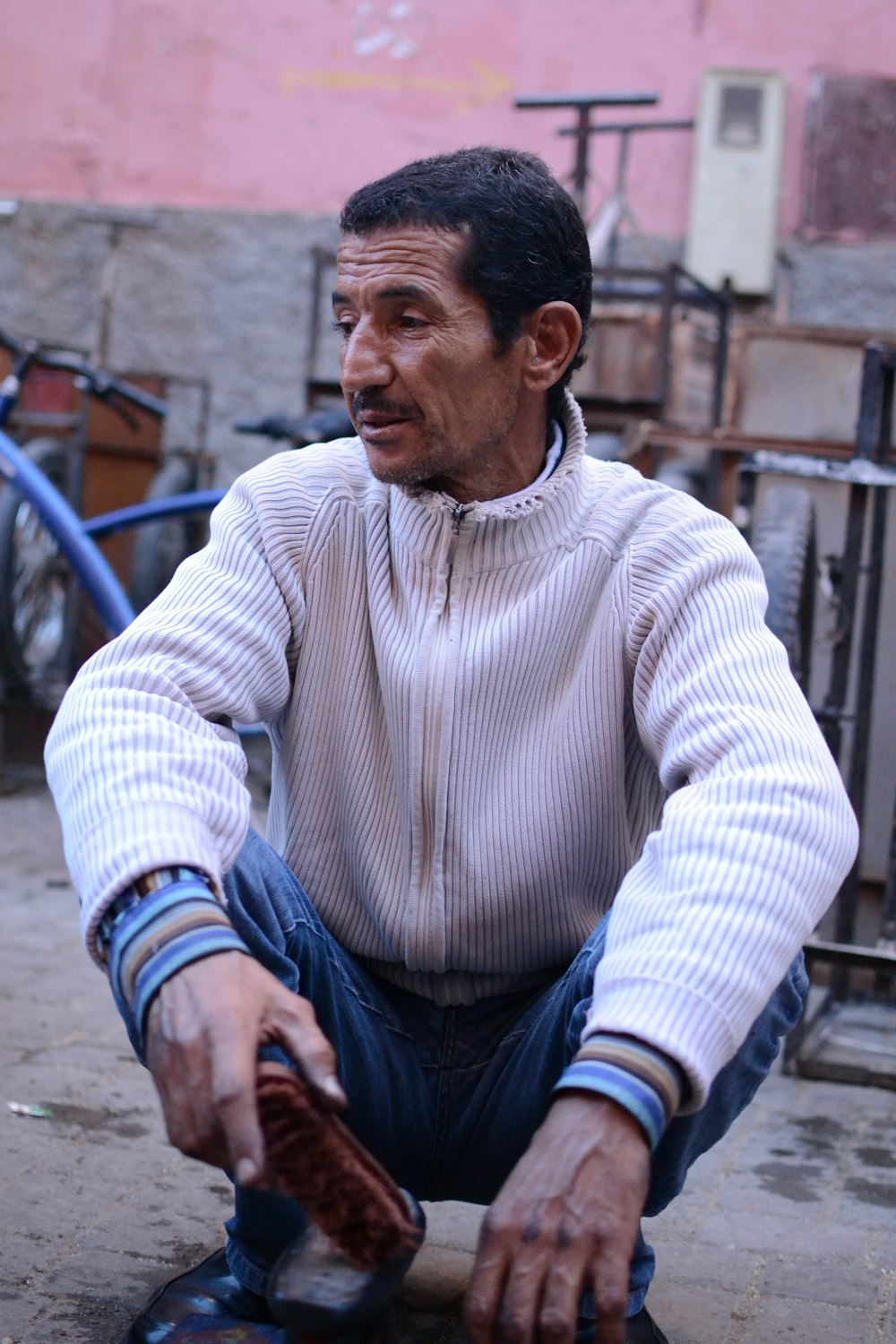 man in white sweater sitting on concrete bench during daytime