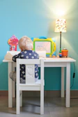 A toddler proudly coloring a bright, playful activity book at a sunny kitchen table.