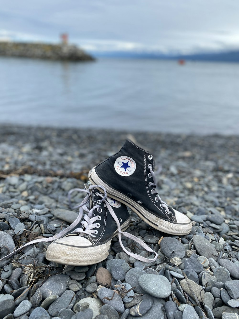 black converse all star high top sneakers on rocky shore