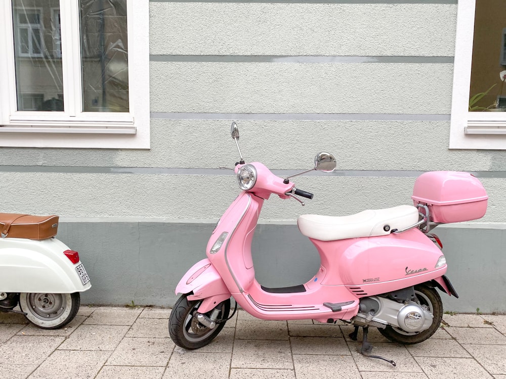 pink and black motor scooter parked beside white concrete building