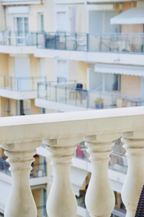 A close-up of freshly painted railings on a balcony overlooking a leafy neighborhood.