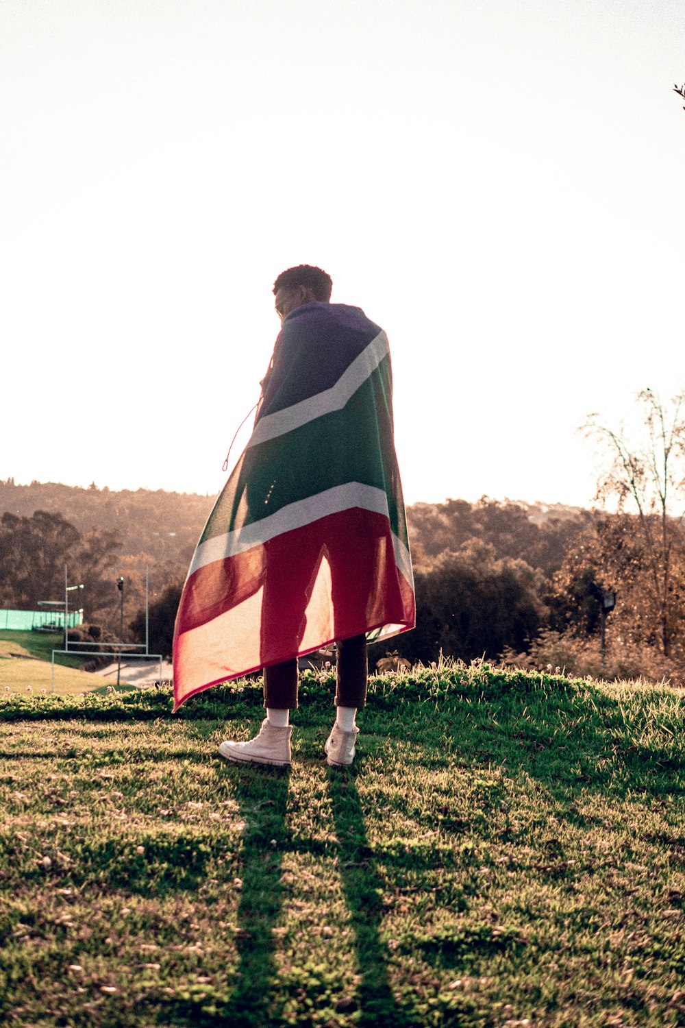 man in green and black striped hoodie standing on green grass field during daytime