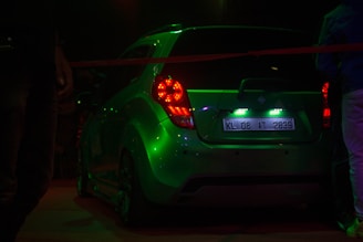 Side view of a black car with custom neon green decals glowing at dusk