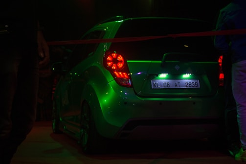 Side view of a black car with custom neon green decals glowing at dusk