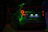 A smiling middle-aged man standing beside his car at dusk, illuminated by neon green lights.