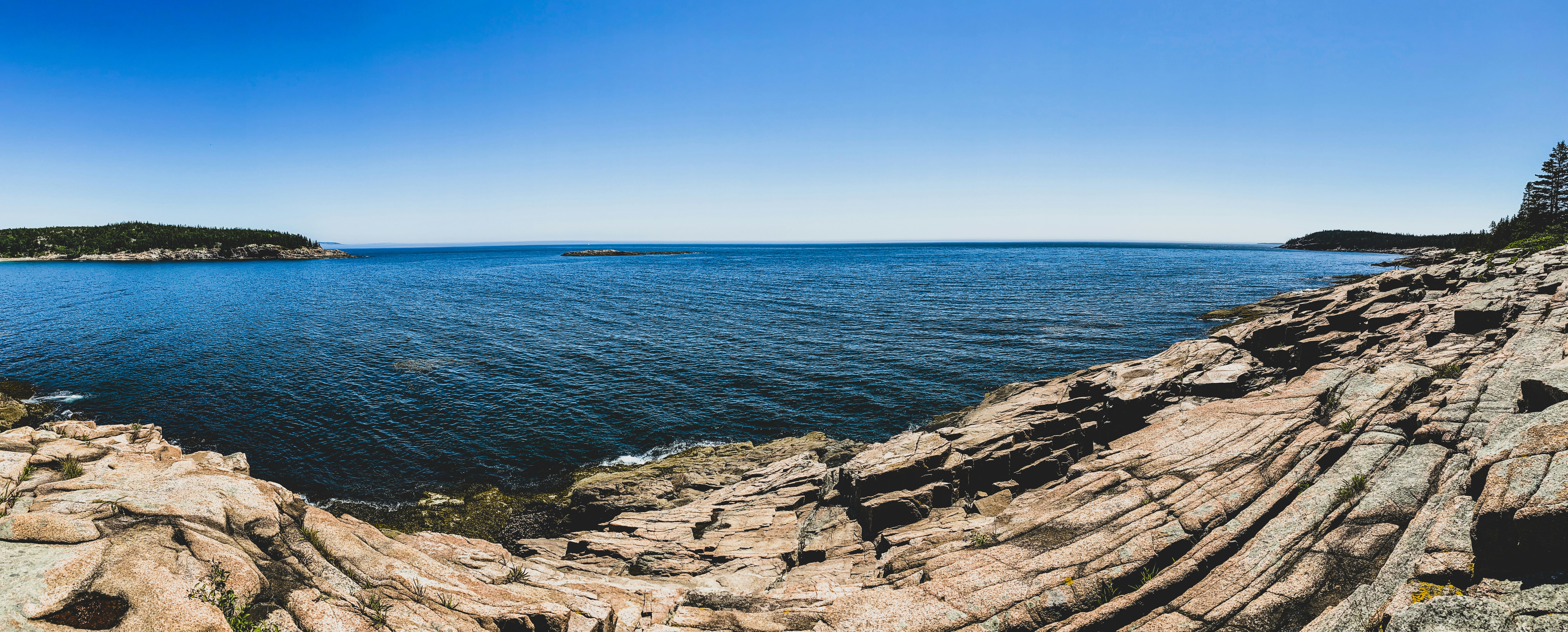 brown rocky shore near blue sea under blue sky during daytime