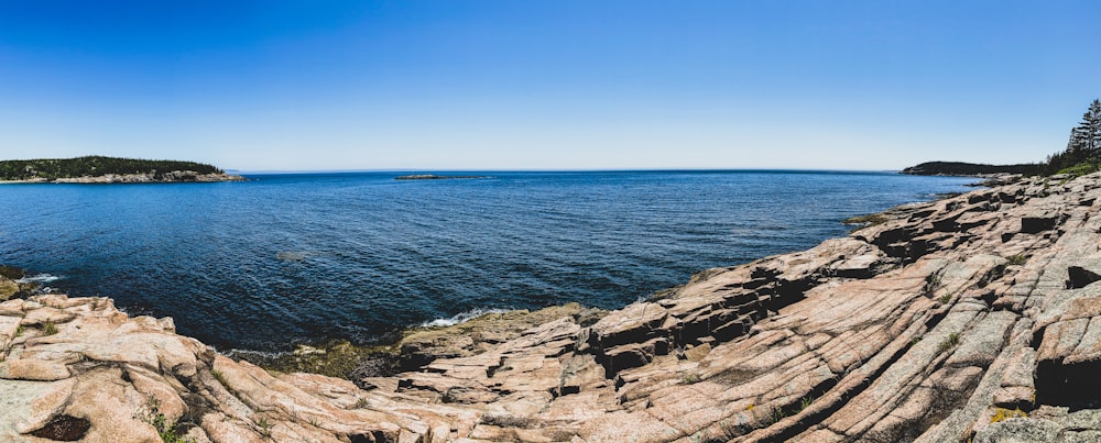 brown rocky shore near blue sea under blue sky during daytime