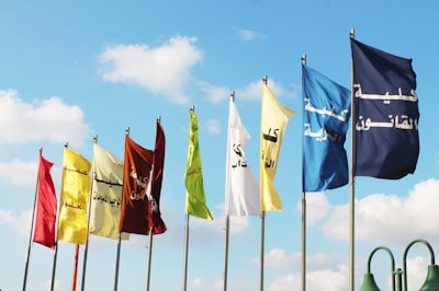 six flags on poles under blue sky during daytime palestine teams background