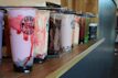 A happy customer picking up their pre-ordered milk tea at a bright, modern melotea store counter