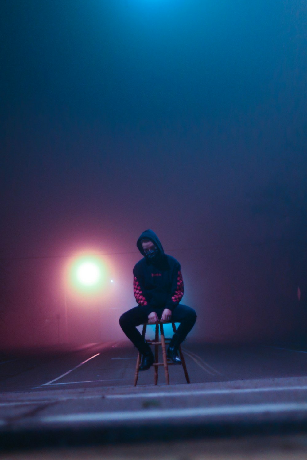 woman in black jacket and pants sitting on black metal bar during night time