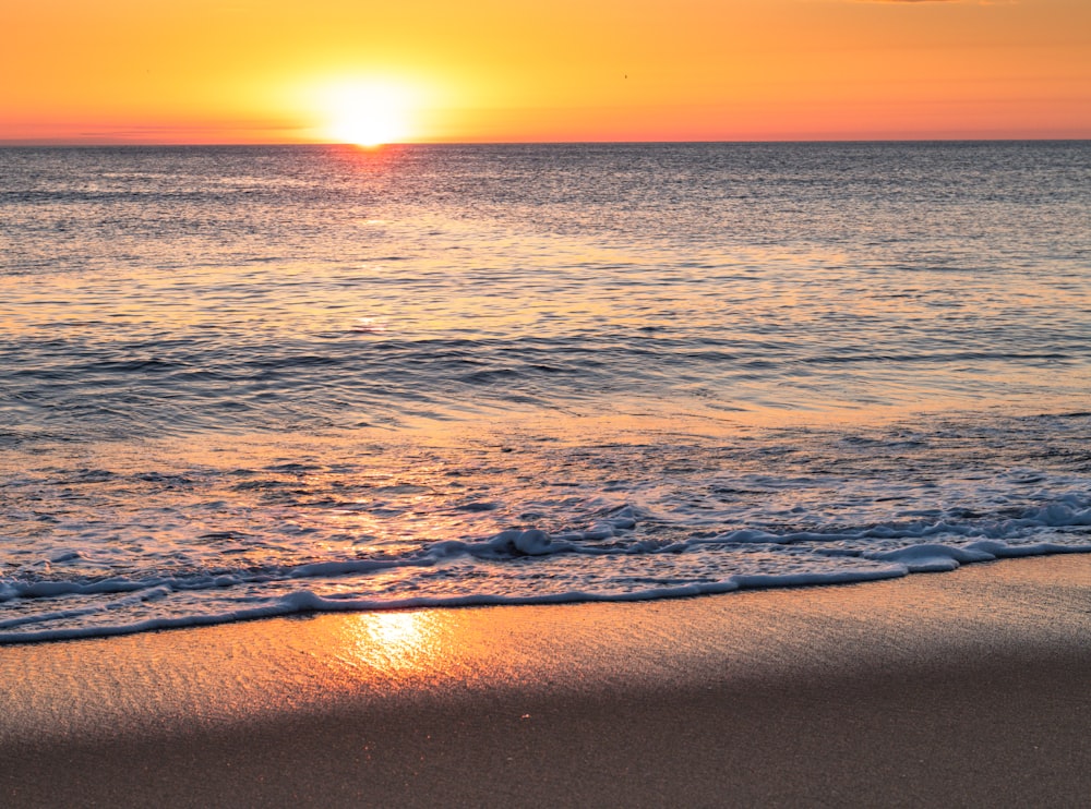 ocean waves crashing on shore during sunset