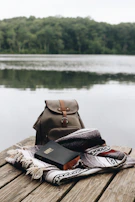A serene lakeside scene with a book resting on a wooden bench.