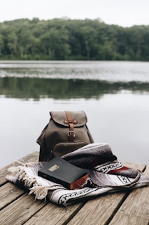 A serene sunrise over a calm lake with a Bible and notebook resting on a wooden dock.