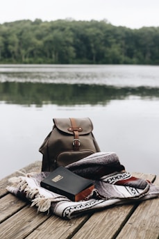 A serene sunrise over a calm lake with a Bible and notebook resting on a wooden dock.