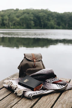 A serene lakeside scene with a journal and camera resting on a bench.