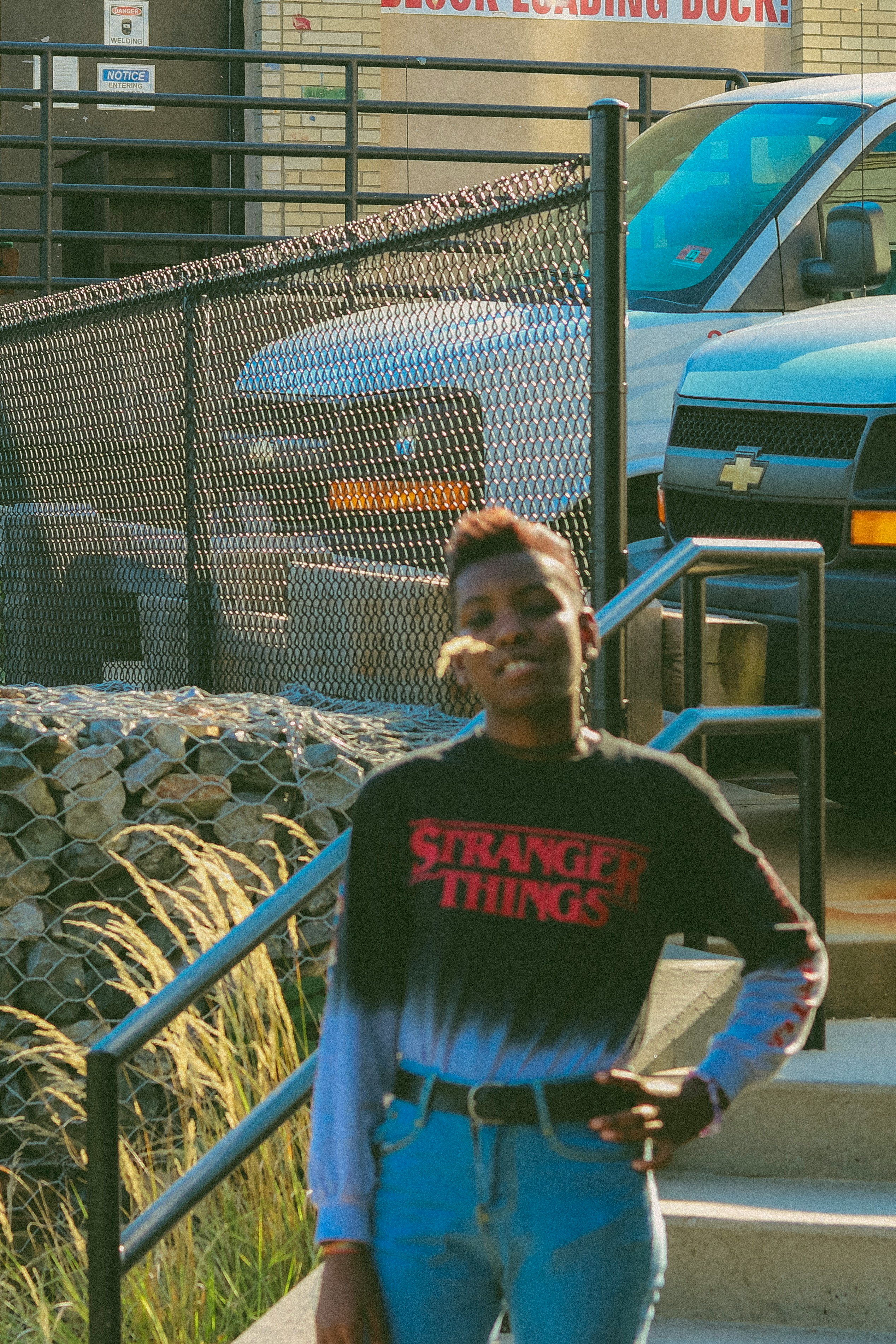 man in black and white sweater standing beside gray metal fence during daytime