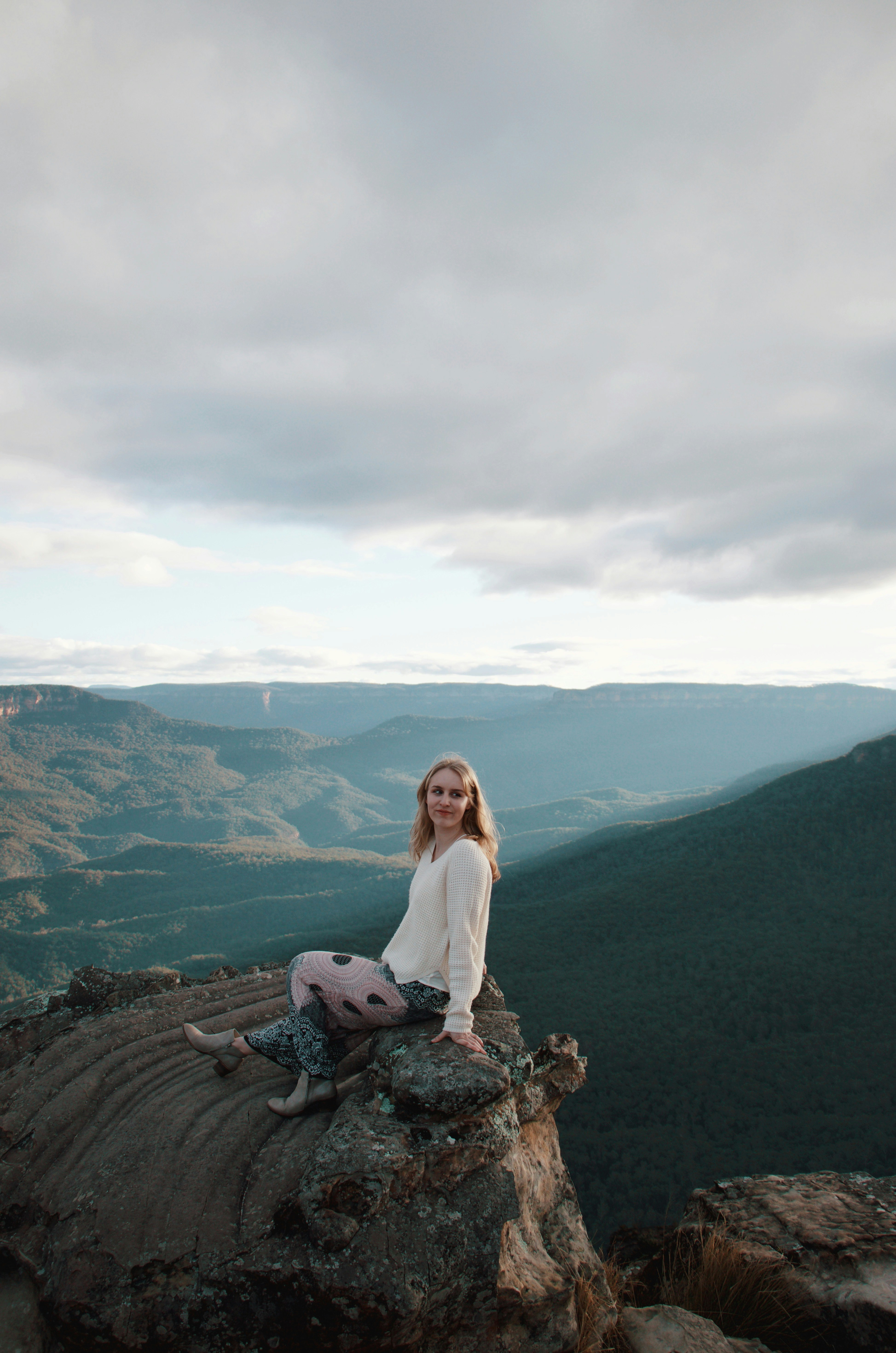 woman in white long sleeve shirt sitting on rock
