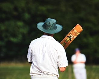 man in white shirt and brown pants wearing brown cowboy hat standing on green grass field