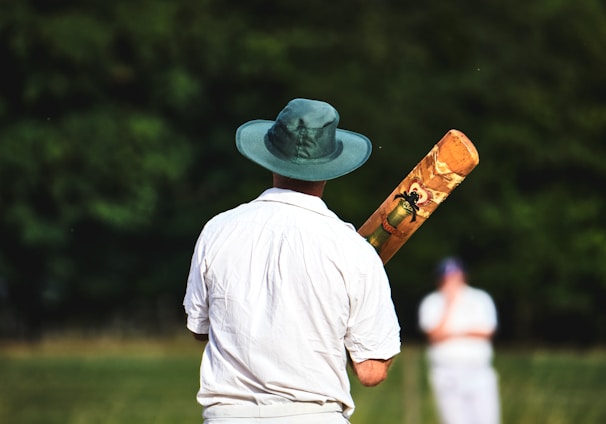 man in white shirt and brown pants wearing brown cowboy hat standing on green grass field