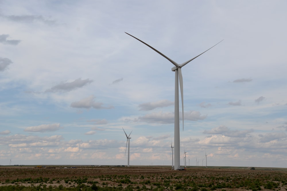 Weiße Windkraftanlagen auf braunem Feld unter weißen Wolken tagsüber