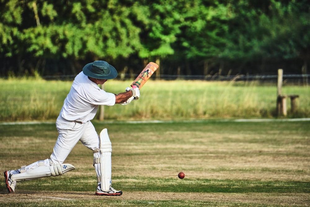 man in white pants and blue baseball mitt holding baseball bat during daytime