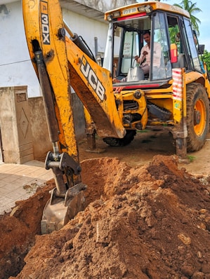 yellow and black excavator on brown soil