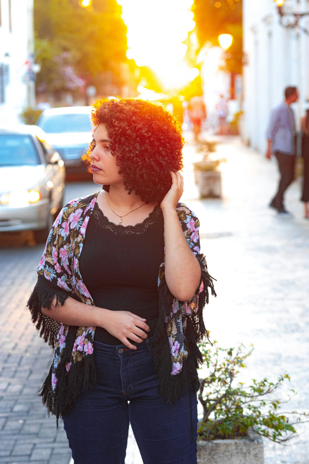 woman in black and pink floral dress standing on sidewalk during daytime