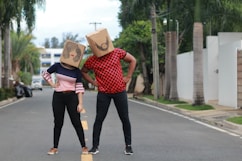 man and woman holding brown cardboard box walking on the street during daytime
