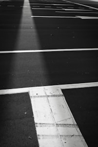 A close-up of a freshly painted bright white parking lot line against smooth black asphalt under a clear sky.