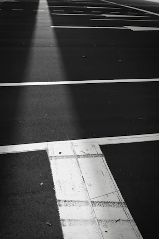 A technician carefully painting bright white parking lines on an asphalt lot under a sunny sky.