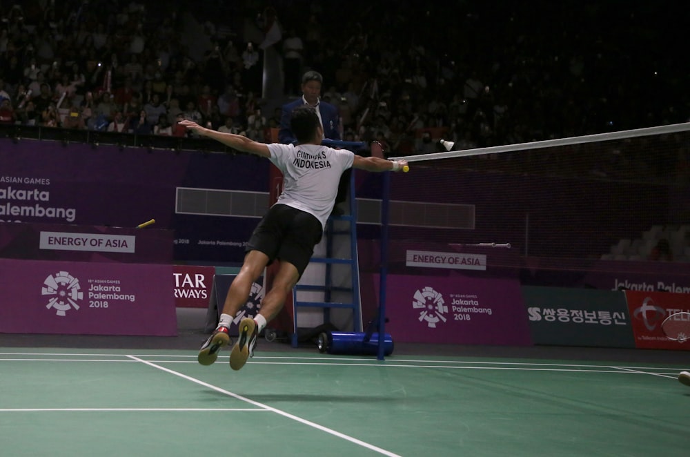 man in white t-shirt and black shorts playing tennis