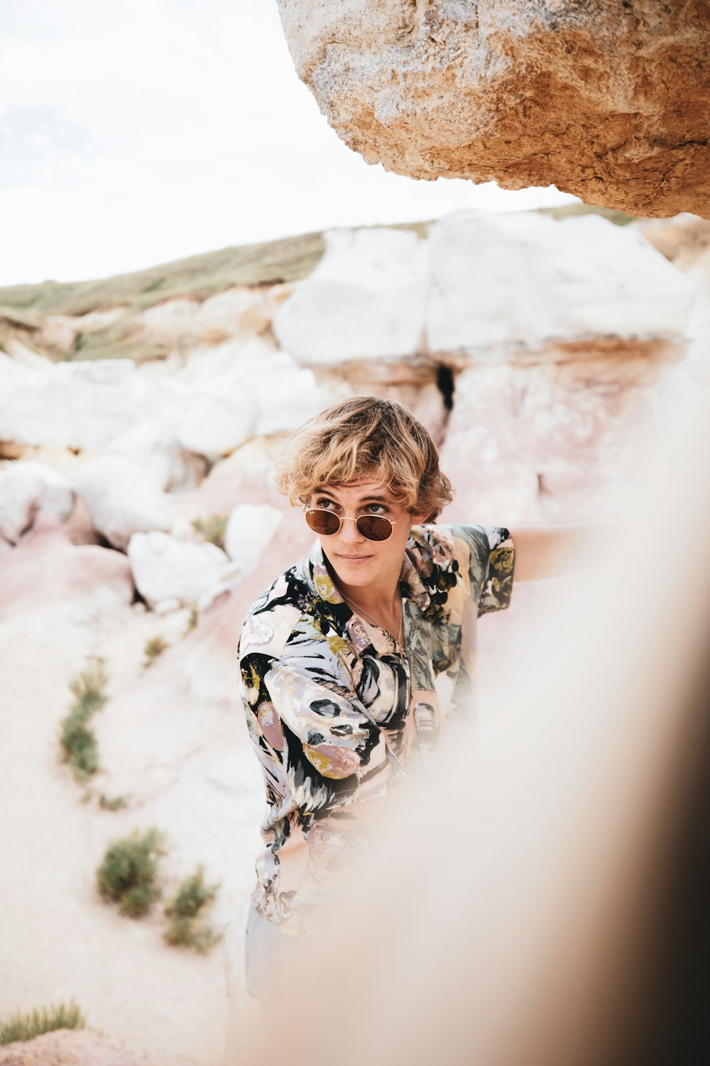 woman in black and white floral long sleeve shirt standing on brown rock during daytime