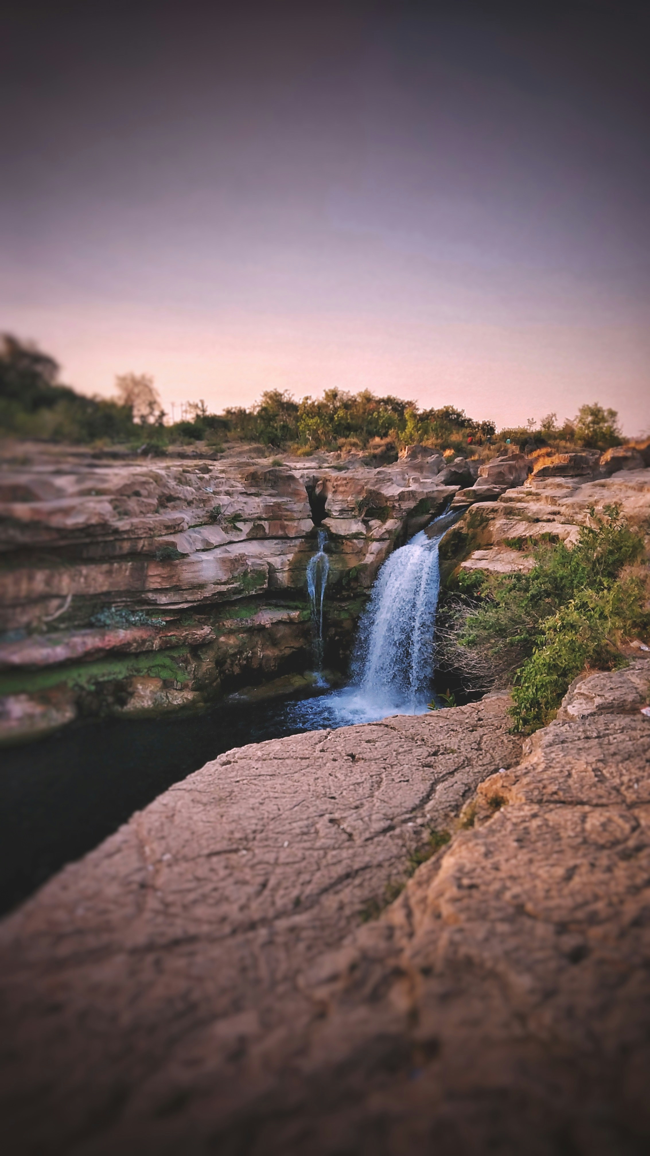 water falls on brown rocky mountain during daytime